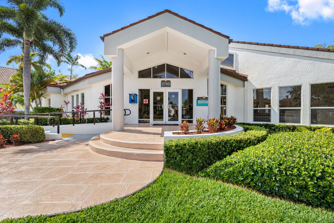 the front entrance of a villa with manicured lawns and hedges