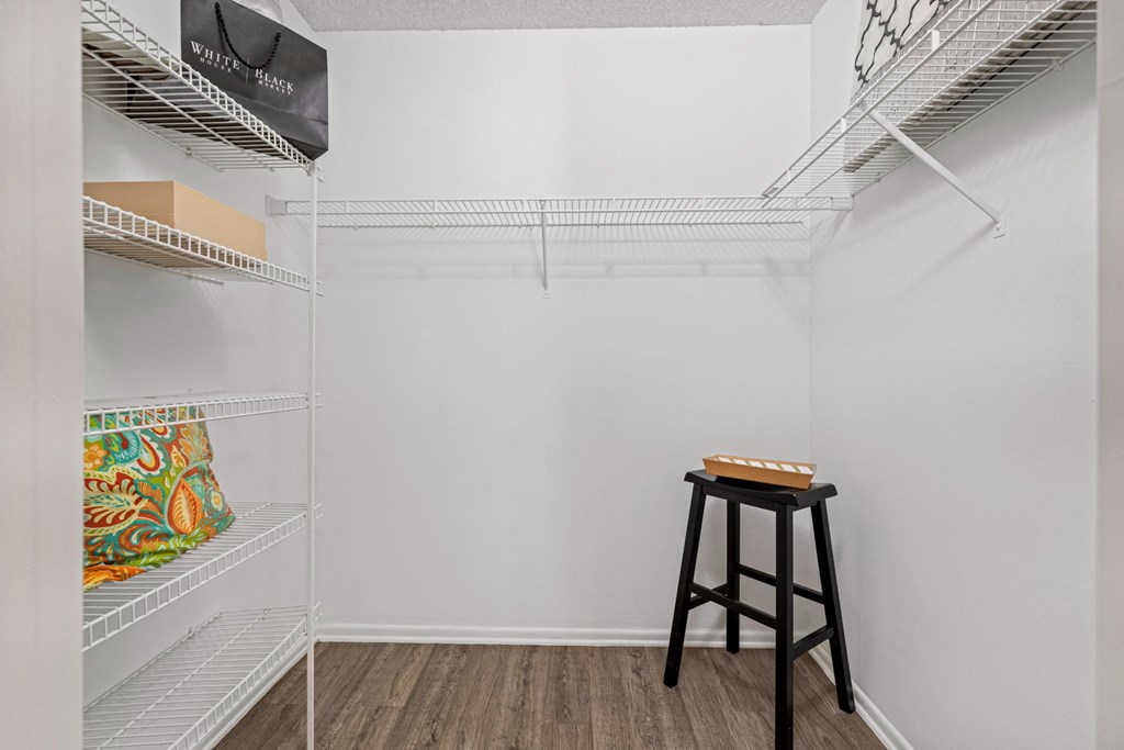 a walk in closet with a bar stool in the corner