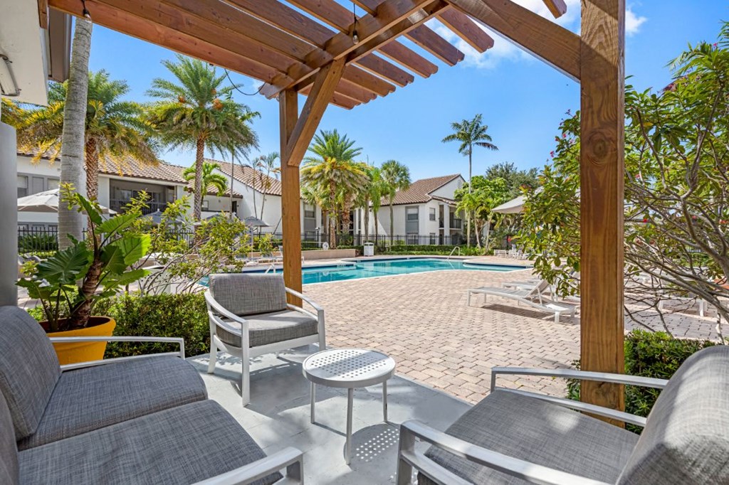 a backyard with a pool and chairs and a pergola