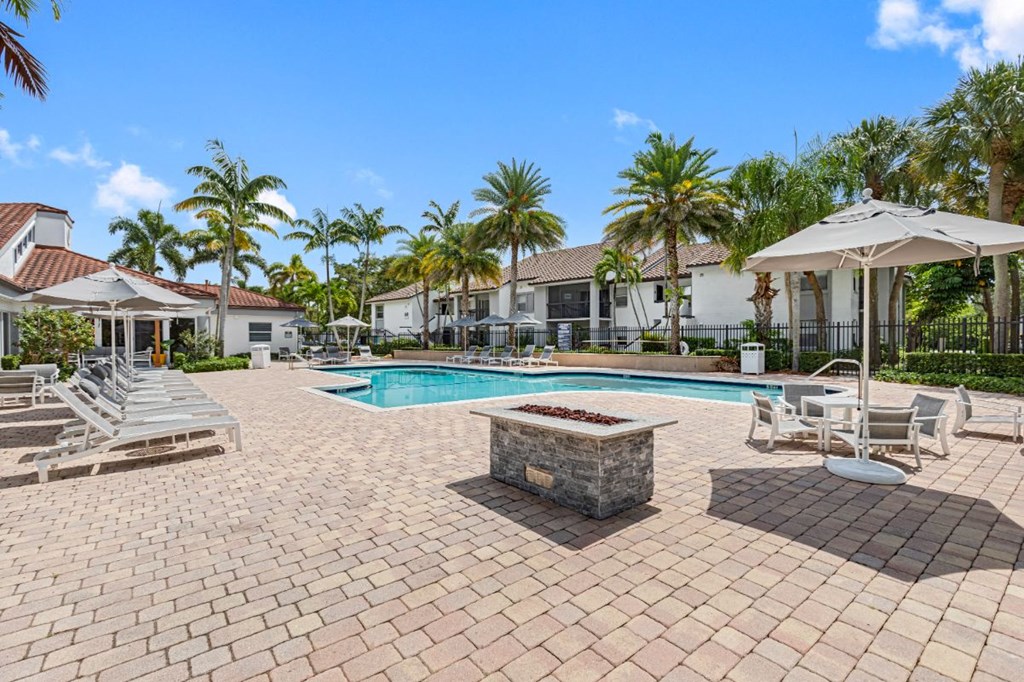 a swimming pool with chairs and umbrellas in front of a house