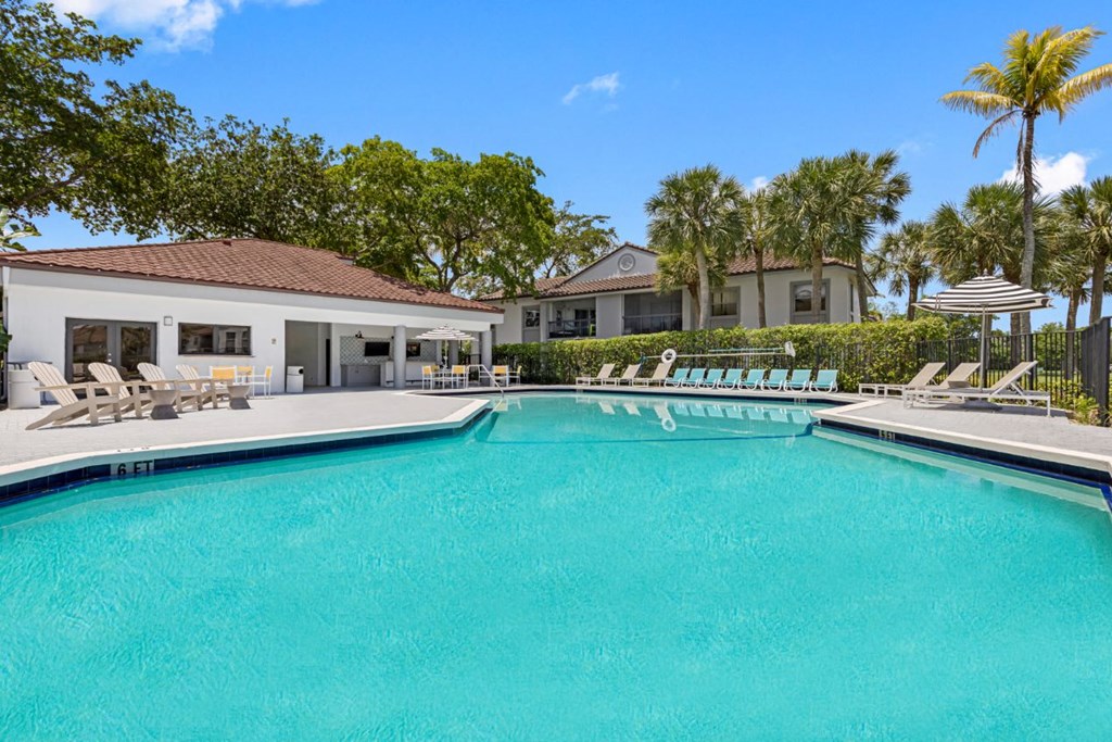 a swimming pool with chairs and a house in the background