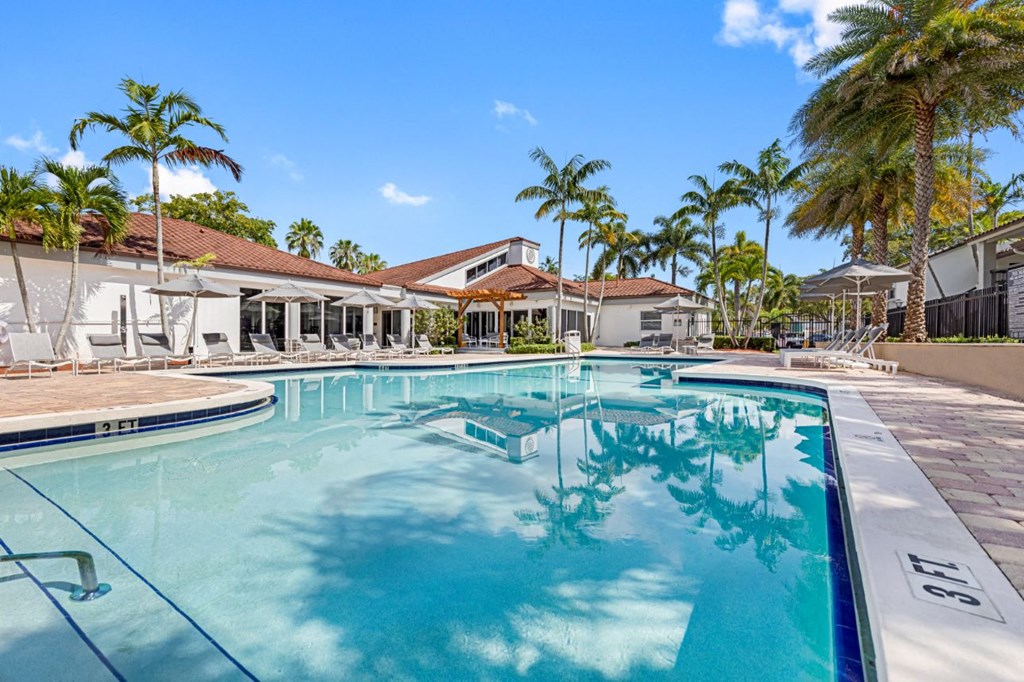 a large swimming pool with palm trees in front of a house