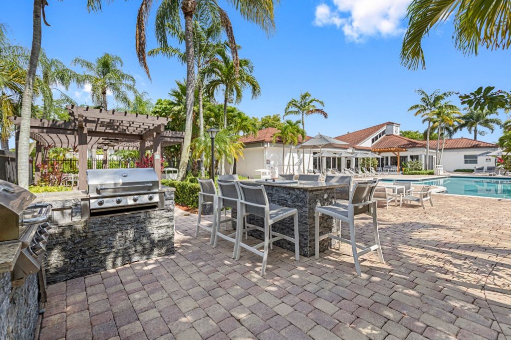 a patio with a barbecue grill and a table and chairs