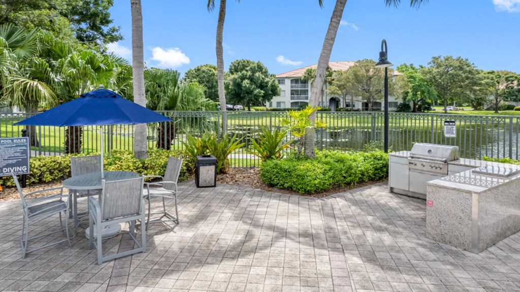 a patio with an umbrella and a table with chairs and a grill