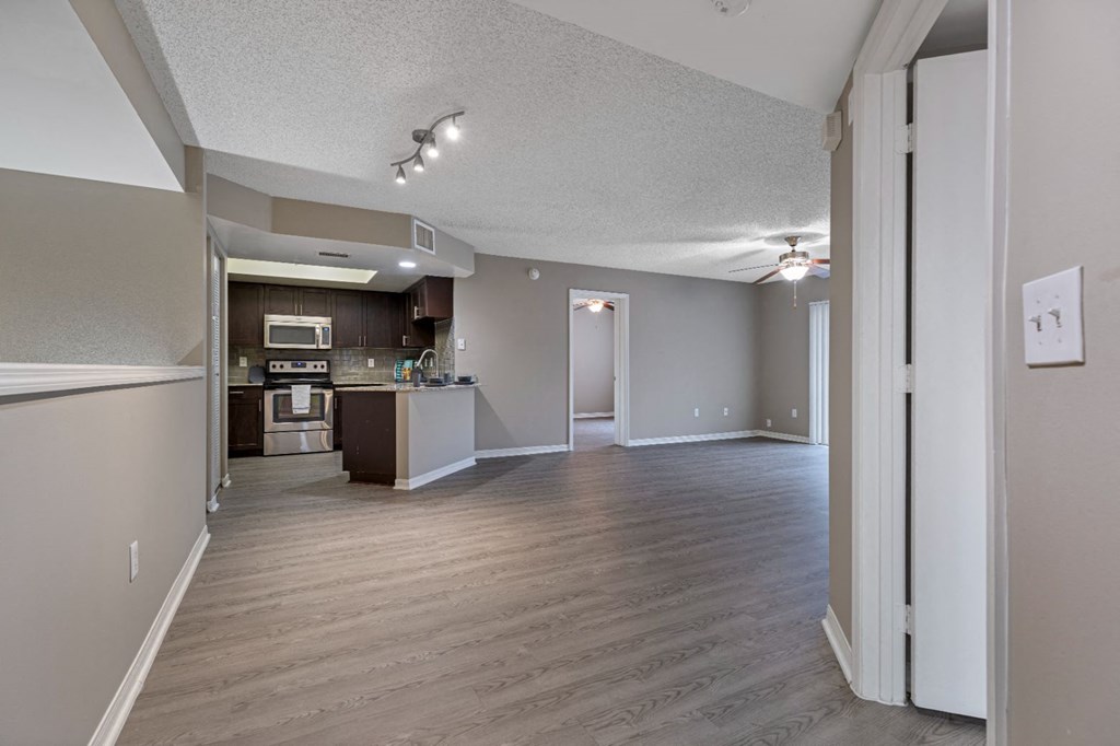an empty living room and kitchen with wood floors