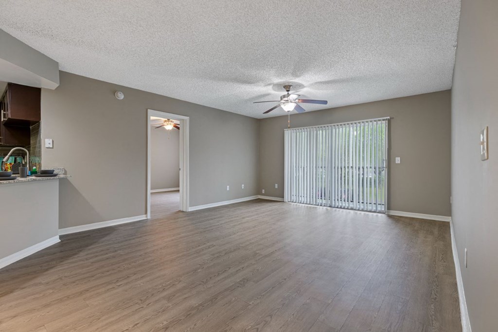 an empty living room with a ceiling fan and a window