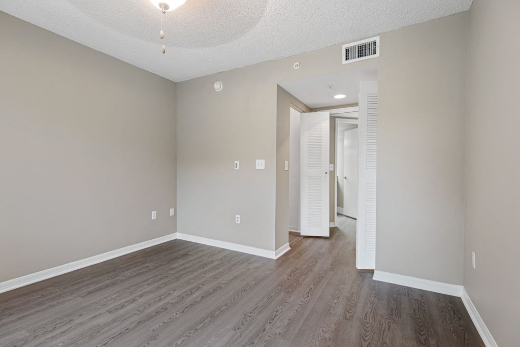 an empty living room and hallway with wood flooring and white walls