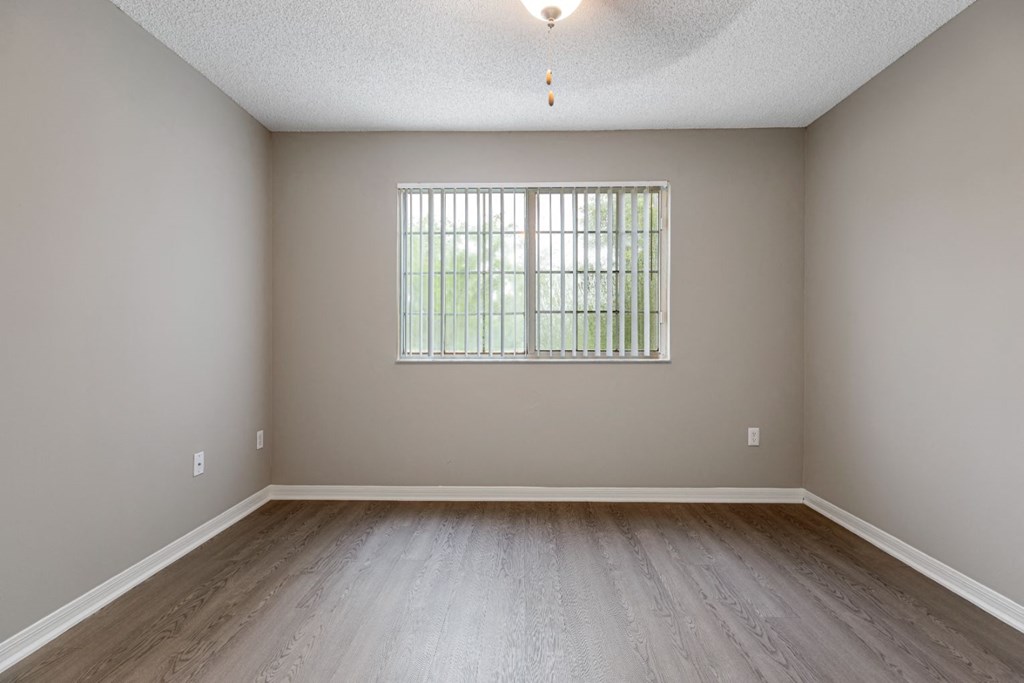 an empty room with wood floors and a window