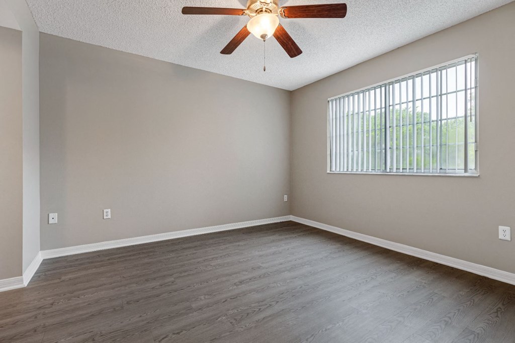 an empty living room with a ceiling fan and a window