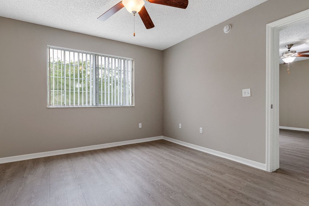 an empty living room with a ceiling fan and a window