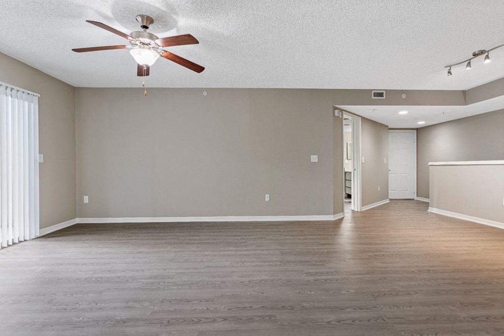 an empty living room with a ceiling fan