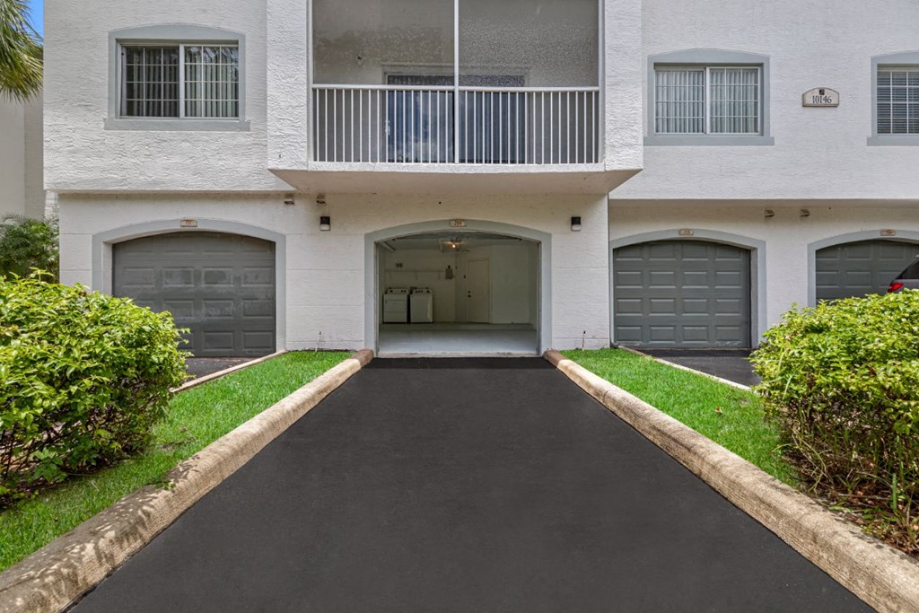 the front entrance to a white building with two garage doors