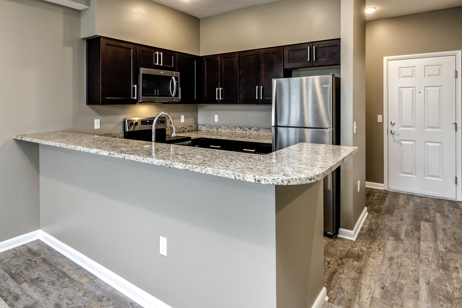 Large kitchen island with dark cabinets at The Apartments at Lux 96 in Papillion, NE