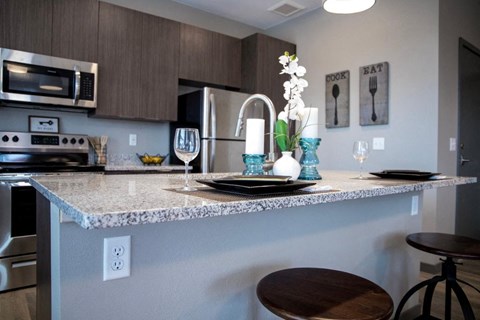 A kitchen with a granite countertop and a stainless steel refrigerator.