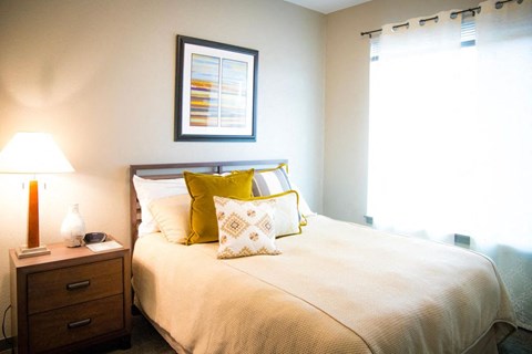 A bedroom with a bed, nightstand, and a picture on the wall.