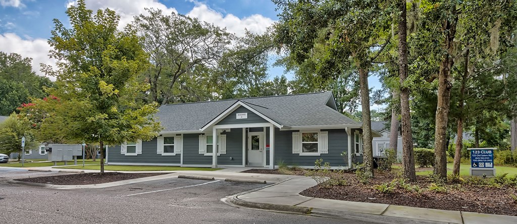 a green house with trees and a parking lot