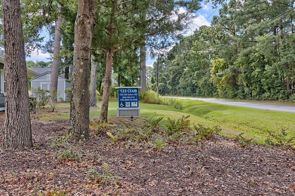 a sign on the side of a road next to trees