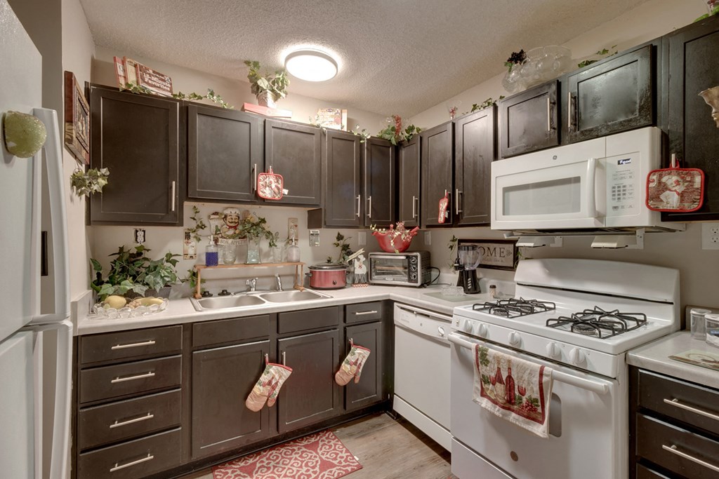 a christmas themed kitchen with white appliances and dark cabinets