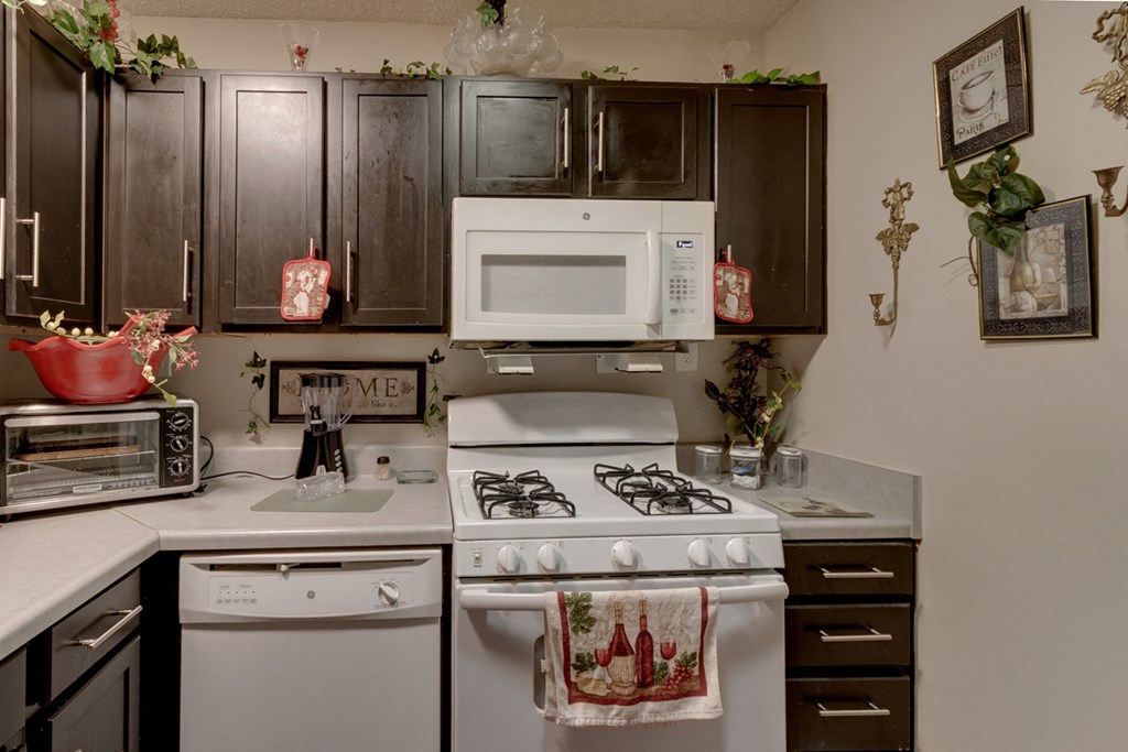 a kitchen with white appliances and dark cabinets