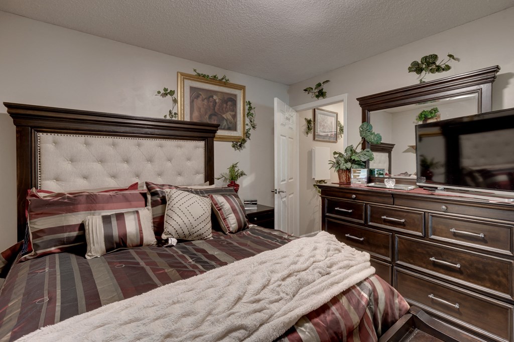 a bedroom with a bed and a dresser and a tv