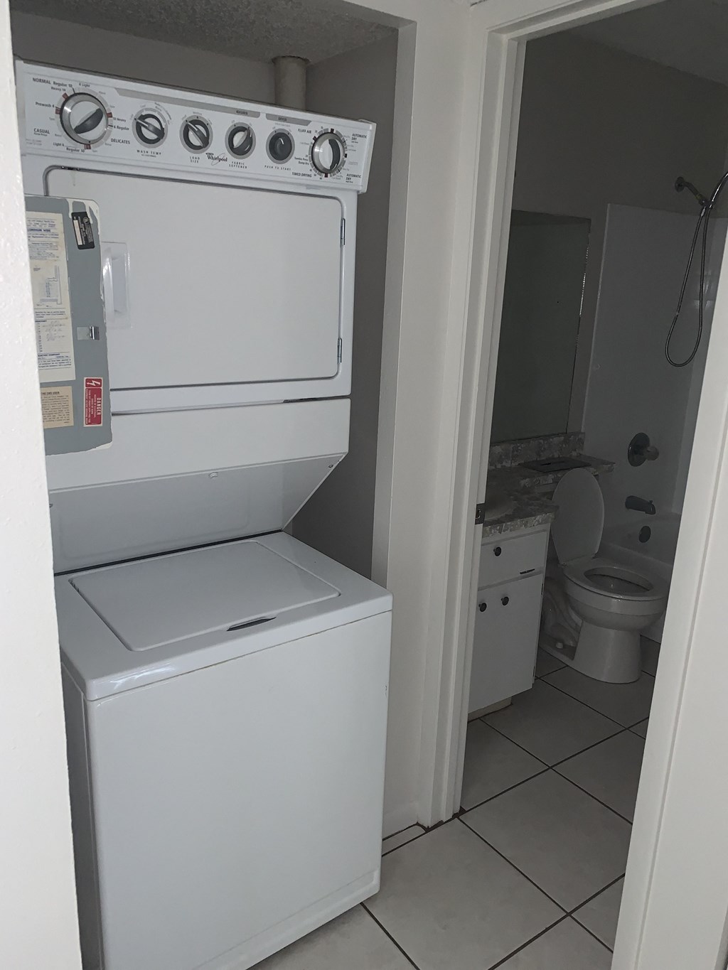 a white washer and dryer in a bathroom with a toilet