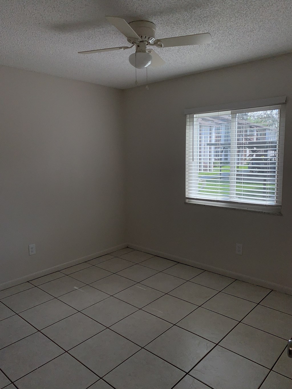 an empty room with a ceiling fan and a window