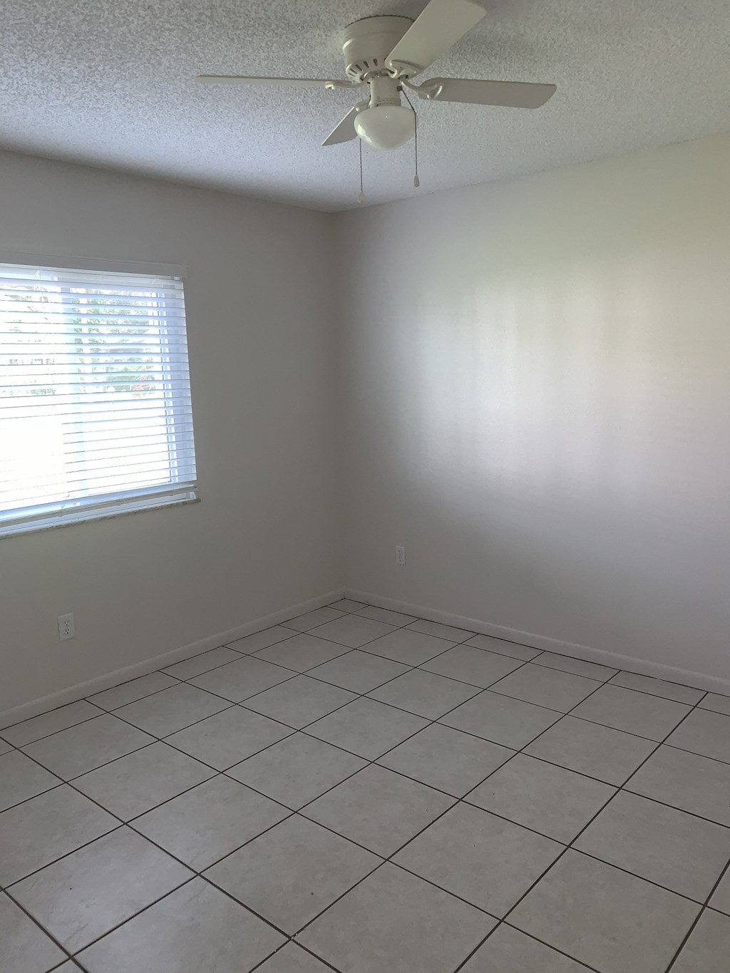 an empty room with a ceiling fan and a window