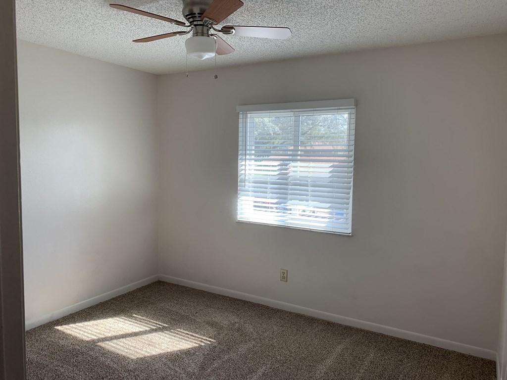 an empty room with a window and a ceiling fan
