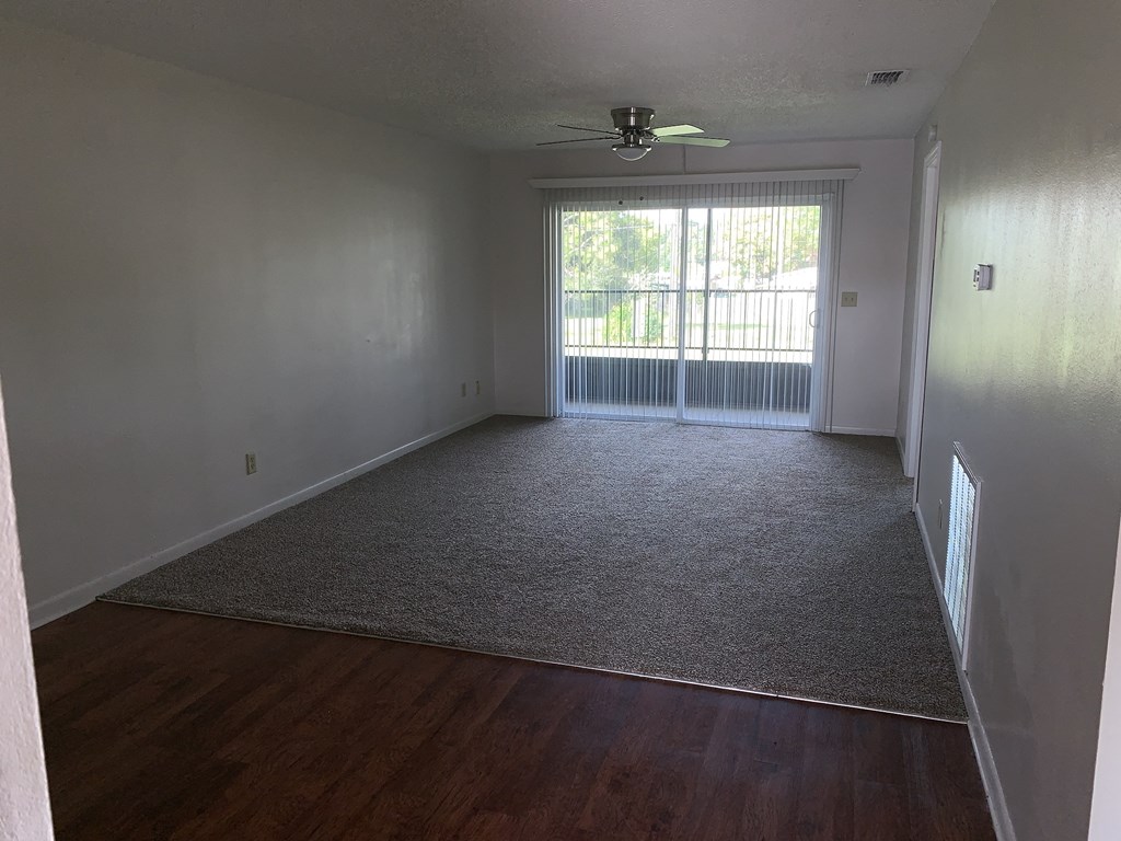 an empty living room with wood floors and a window