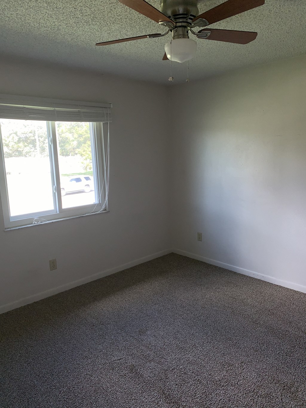 an empty room with a ceiling fan and a window