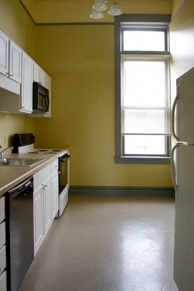 a kitchen with white cabinets and a window and a refrigerator
