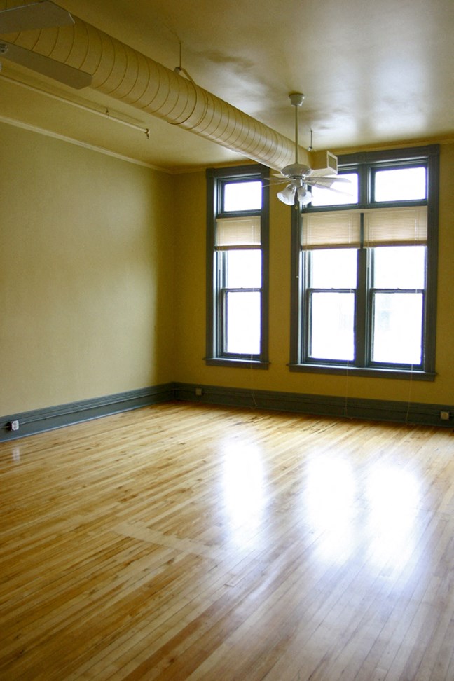 an empty room with windows and a wooden floor