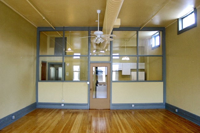 an empty room with a wood floor and a ceiling fan