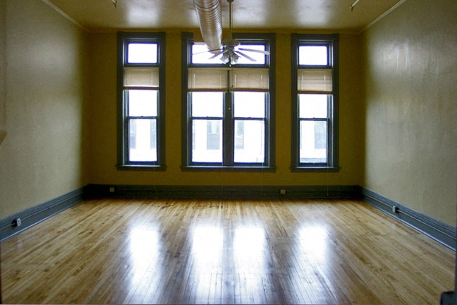 an empty room with three windows and a wooden floor