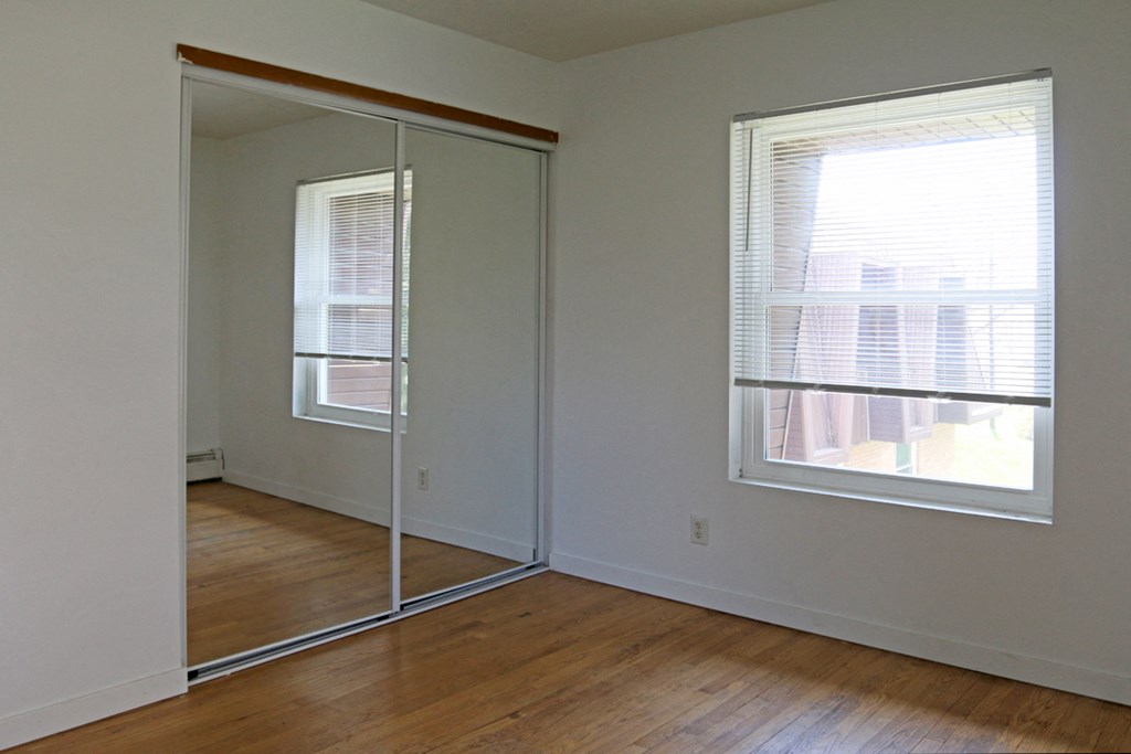 an empty room with a mirrored closet and a window