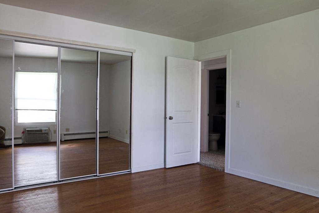 a bedroom with mirrors on the wall and a hard wood floor