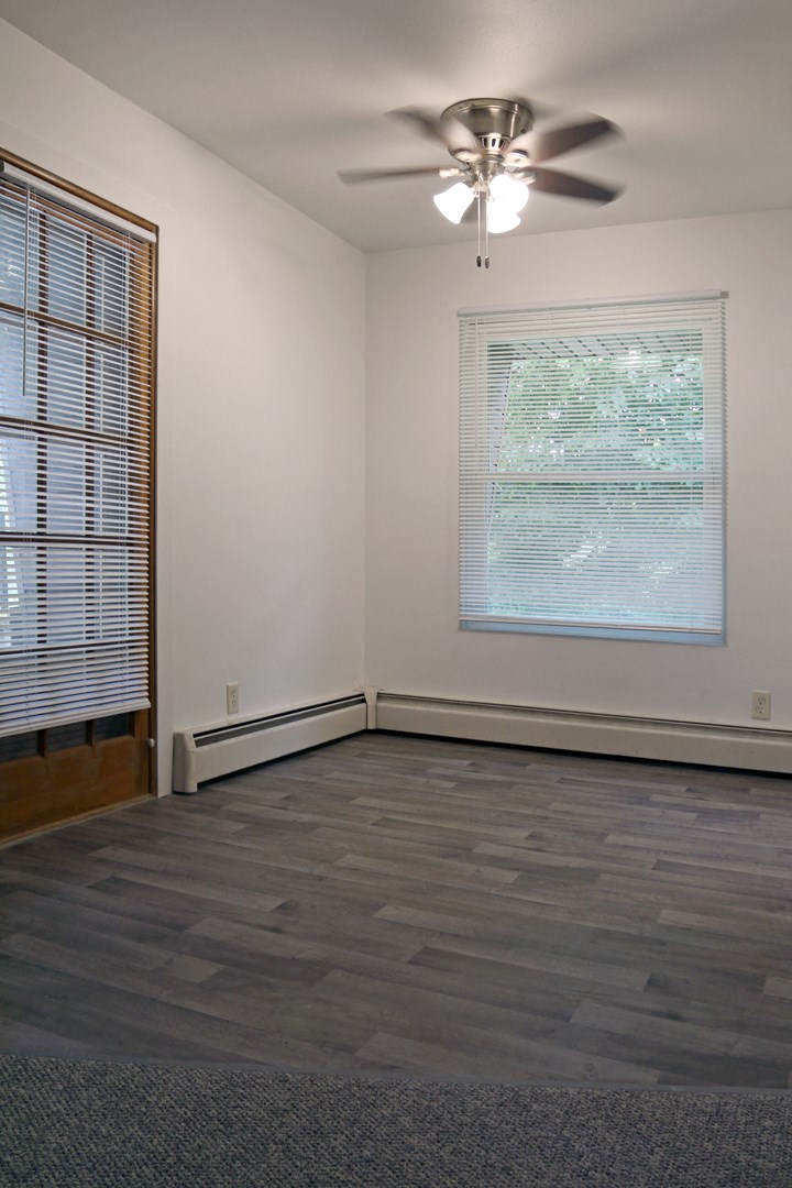 an empty living room with a ceiling fan and a window