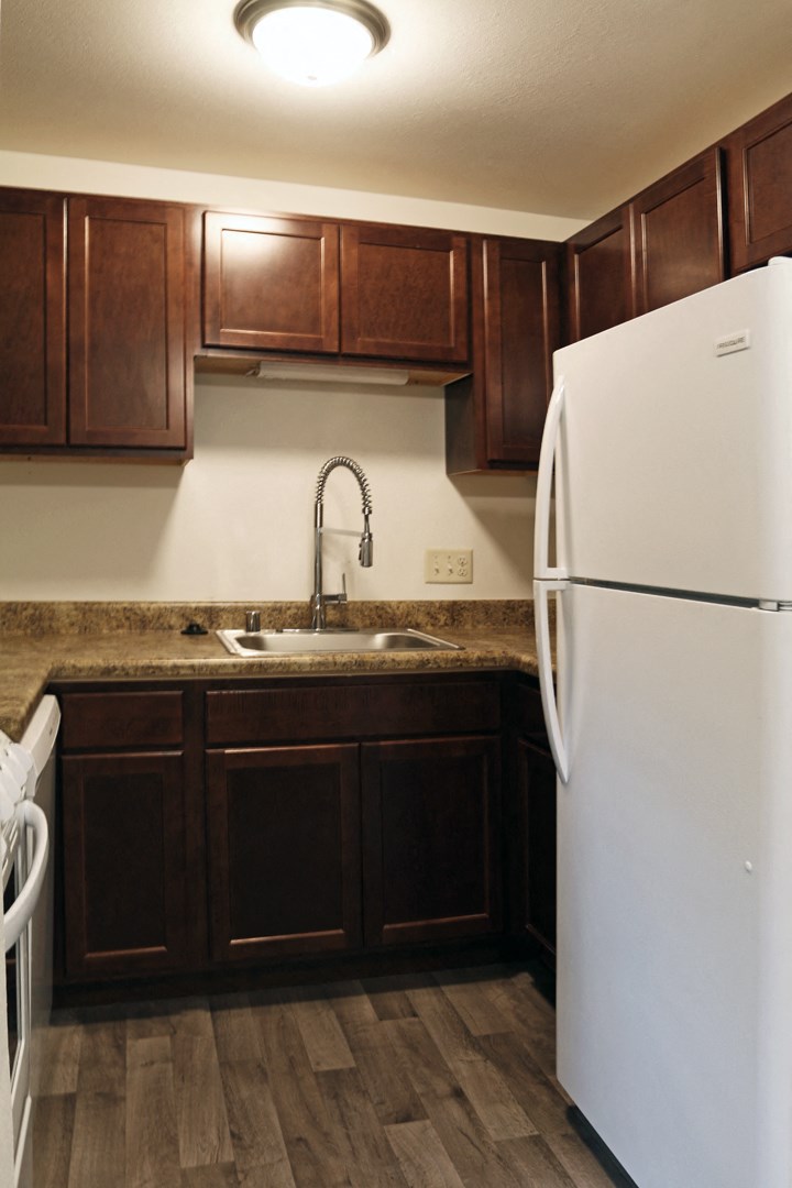 a kitchen with a sink and refrigerator and wooden cabinets