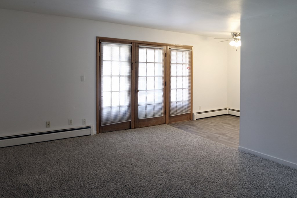 an empty living room with two doors and a carpeted floor
