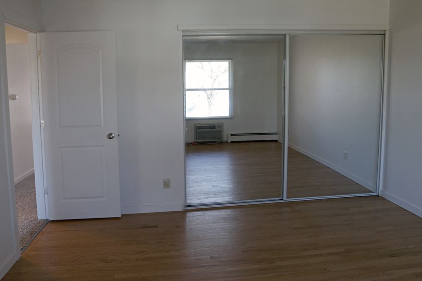 an empty living room with a door open to a mirrored closet