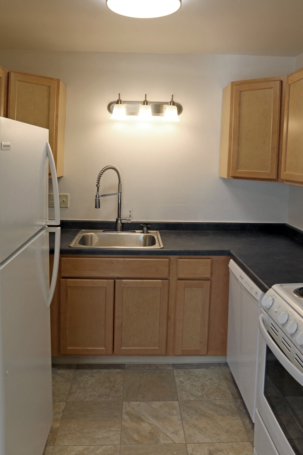 an empty kitchen with a sink and a refrigerator