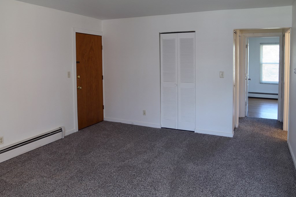 an empty living room with carpet and a door to a bedroom