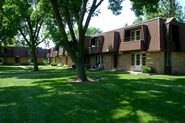 a group of houses on a lawn with trees