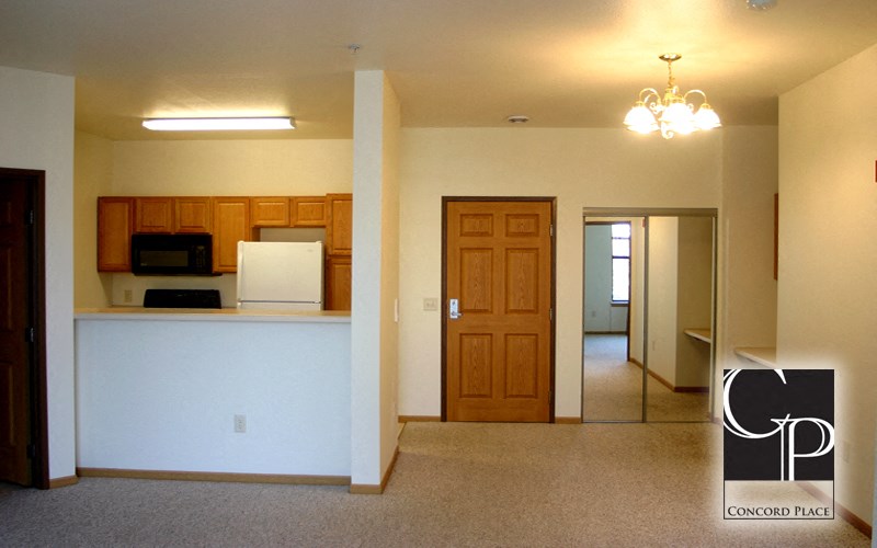 an empty room with a kitchen and a door to a living room