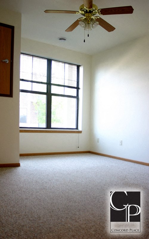 an empty living room with a ceiling fan and a window