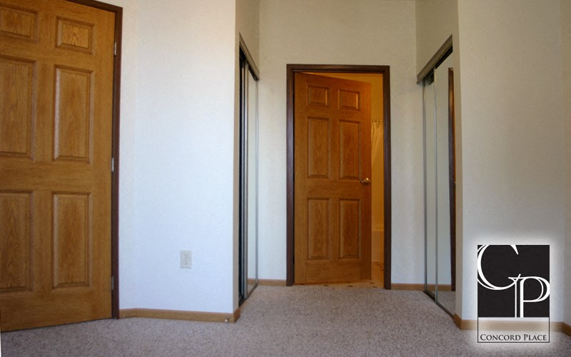 an empty room with two doors and a carpeted floor