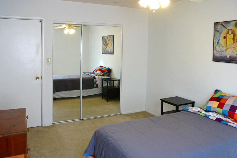 a bedroom with a bed and a mirrored closet