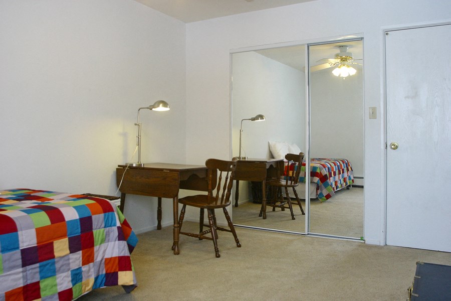 a bedroom with a desk and a mirror and a bed