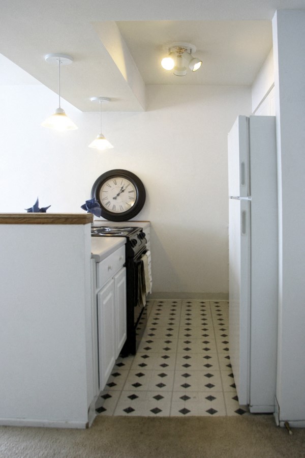 a small kitchen with white cabinets and a clock on the wall