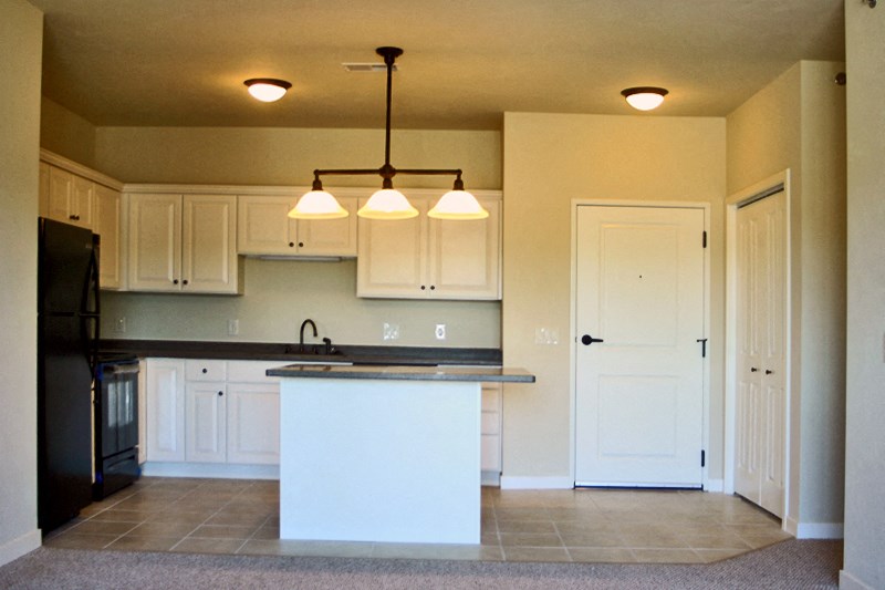 an empty kitchen with white cabinets and a counter top